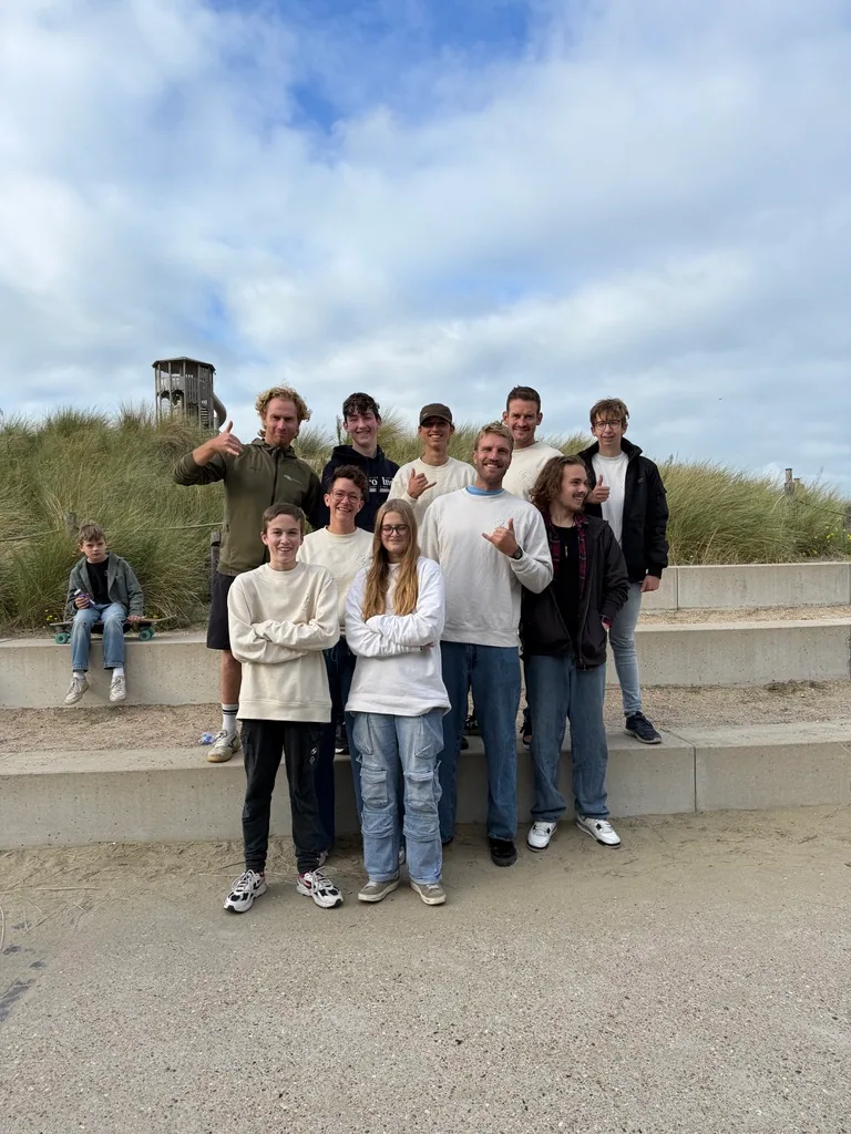 Een groep jongeren en coaches staat samen bij de duinen.