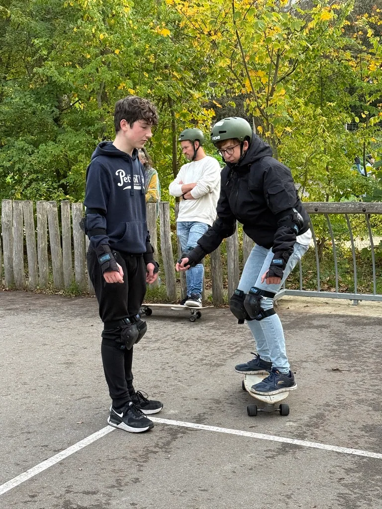 Een coach helpt een jongere om balans te vinden op een surfskateboard.
